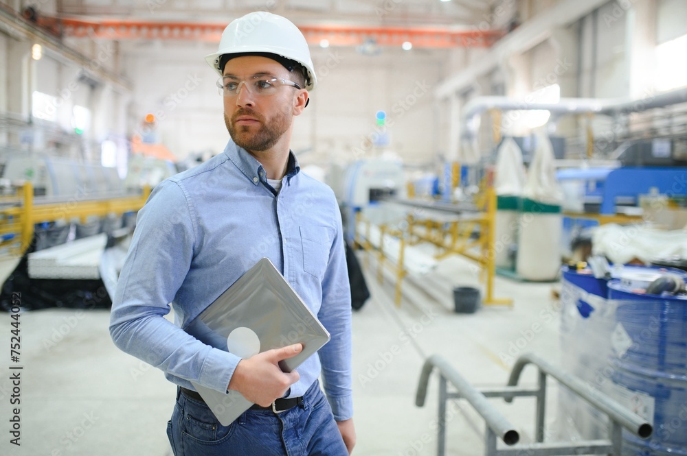 Engineer in hardhat is using a laptop in a heavy industry factory Engineer in hardhat is using a laptop in a heavy industry factory