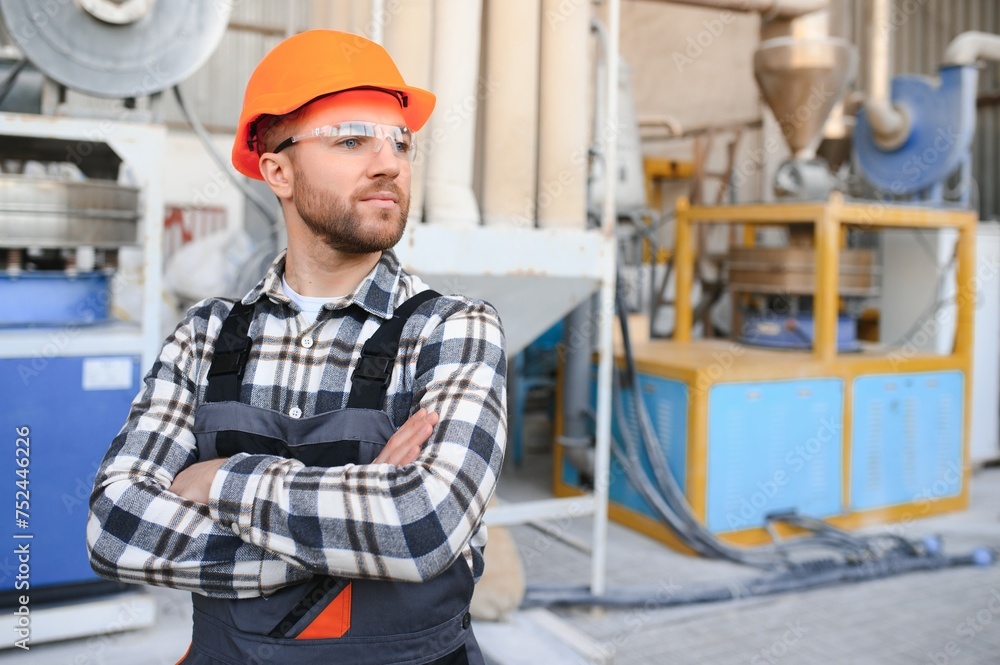 Smiling and happy employee. Industrial worker indoors in factory. Young technician with hard hat Smiling and happy employee. Industrial worker indoors in factory. Young technician with hard hat