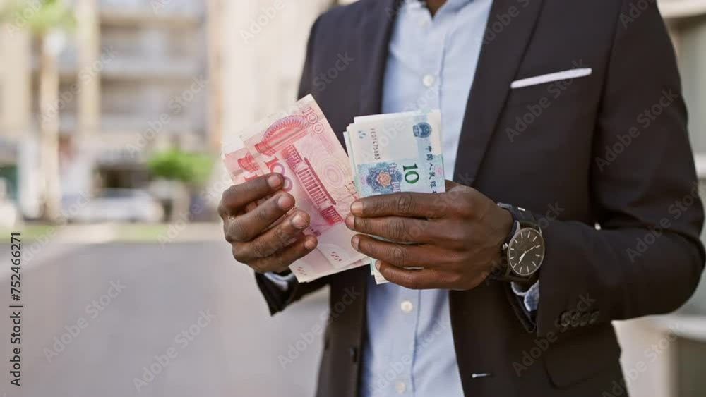 African businessman in suit holding chinese yuan on city street African businessman in suit holding chinese yuan on city street