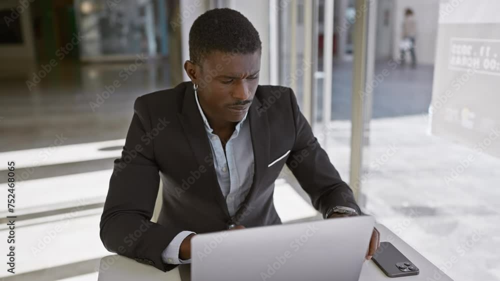 Focused black man using laptop in modern office setting, portraying professionalism and concentration. Focused black man using laptop in modern office setting, portraying professionalism and concentration.