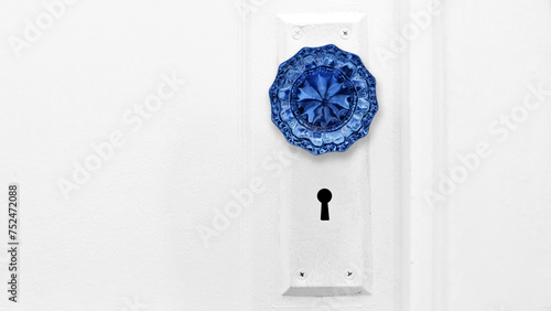 Beautiful close-up photo of a vibrant blue antique crystal door knob on a white interior door with copy space.