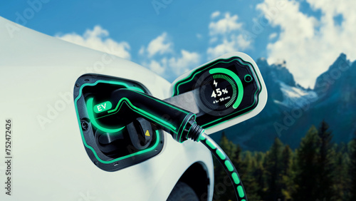 Electric car plug in with charging station,recharge battery by EV charger cable display smart digital battery status hologram in nature and mountain. Energy sustainability technological advance.Peruse