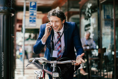 Businessman with bicycle on phone call in city photo