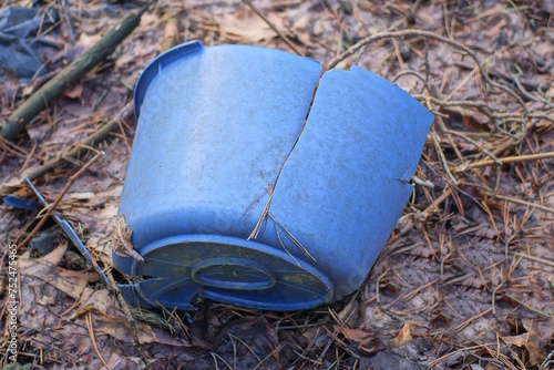 one old empty blue dirty plastic broken bowl stands on the gray ground in the street