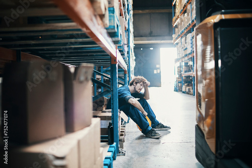 Tired young man taking break from working in warehouse photo