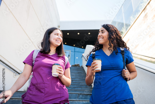 Couple of latin female nurses friends with scrub after work, living clinic down stairs. Medical professionals after work