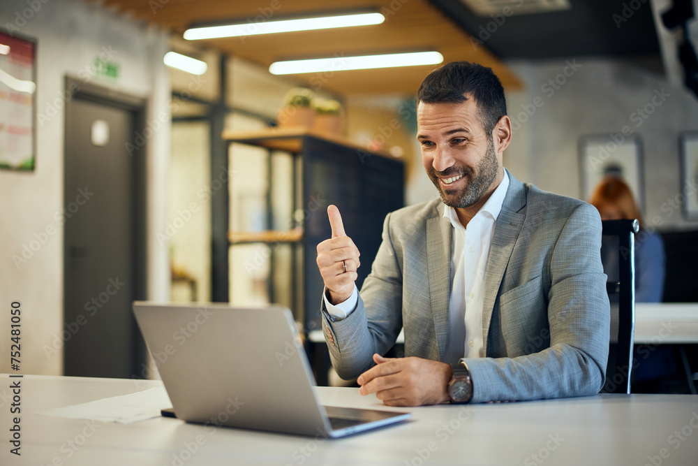 A happy businessman having an online meeting, showing a thumb up. A happy businessman having an online meeting, showing a thumb up.