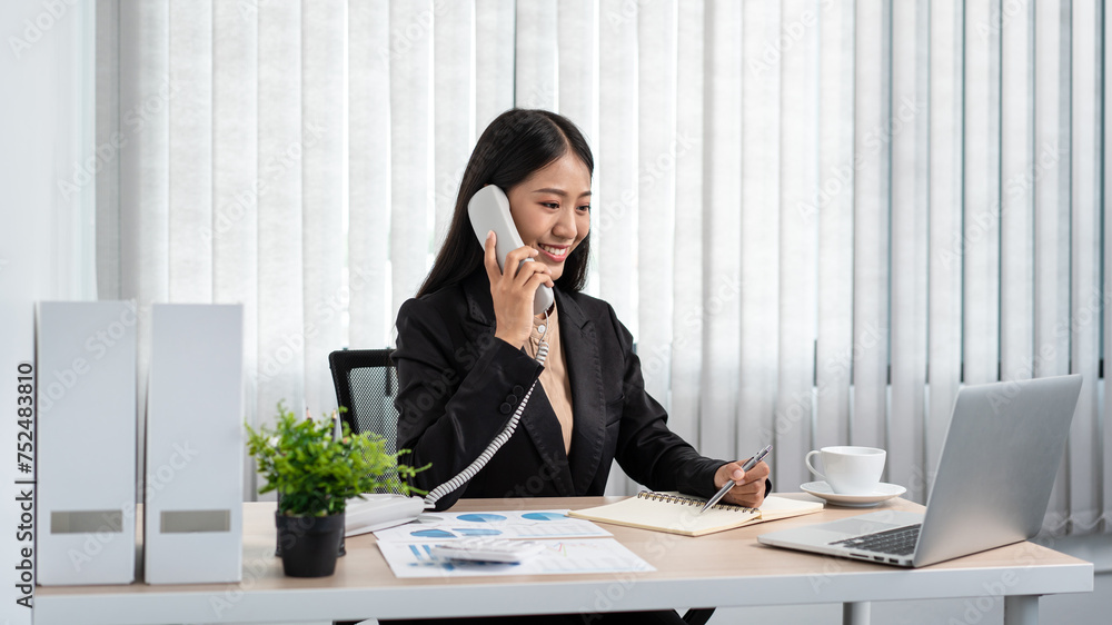 Business woman is receiving call with client to talking about investment of new business and taking notes on notebook Business woman is receiving call with client to talking about investment of new business and taking notes on notebook