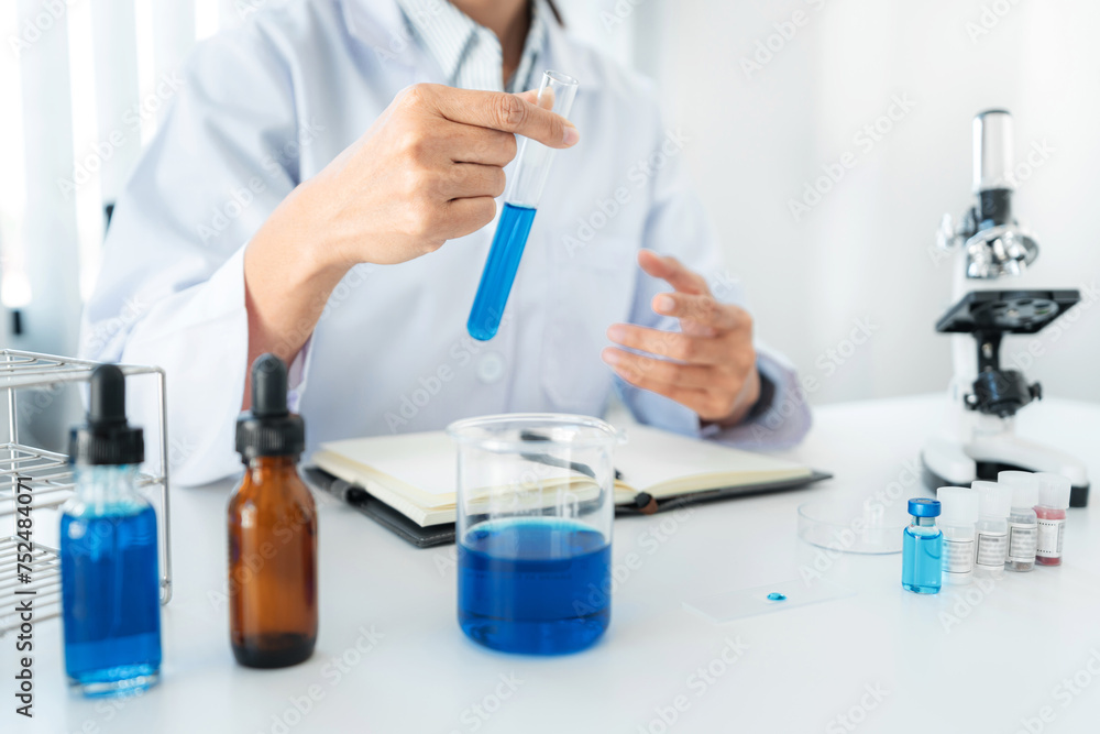 Scientist woman holding test tube to looking reaction on test tube with blue liquid in his hands while working