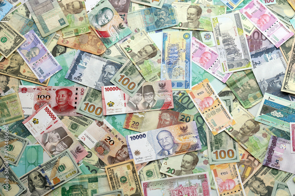 Many banknotes of different currency. Background of big amount of random money bills close up