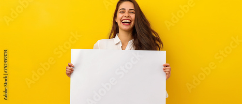 Mulher sorrindo segurando uma placa em branco isolada no fundo amarelo photo