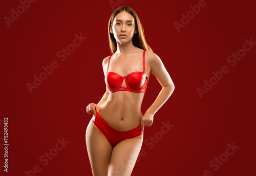 Slender sexy woman in red latex underwear on a red background.