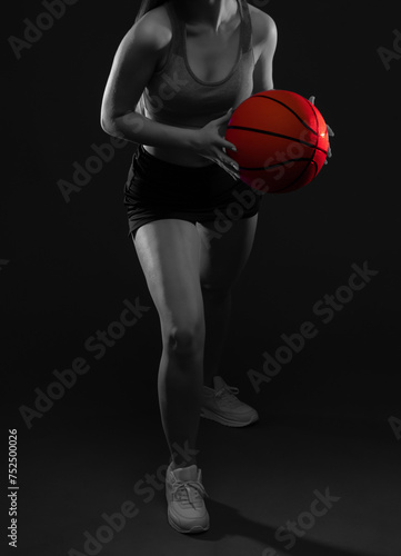 A beautiful slender girl athlete in shorts and a top plays basketball.