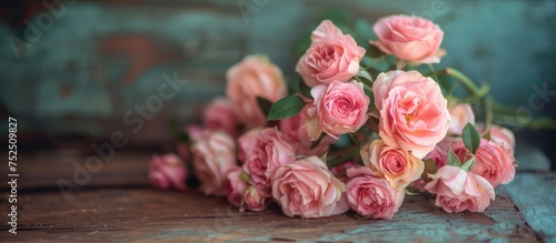 Beautiful pink roses arranged on a rustic wooden table in a charming country setting © TheWaterMeloonProjec