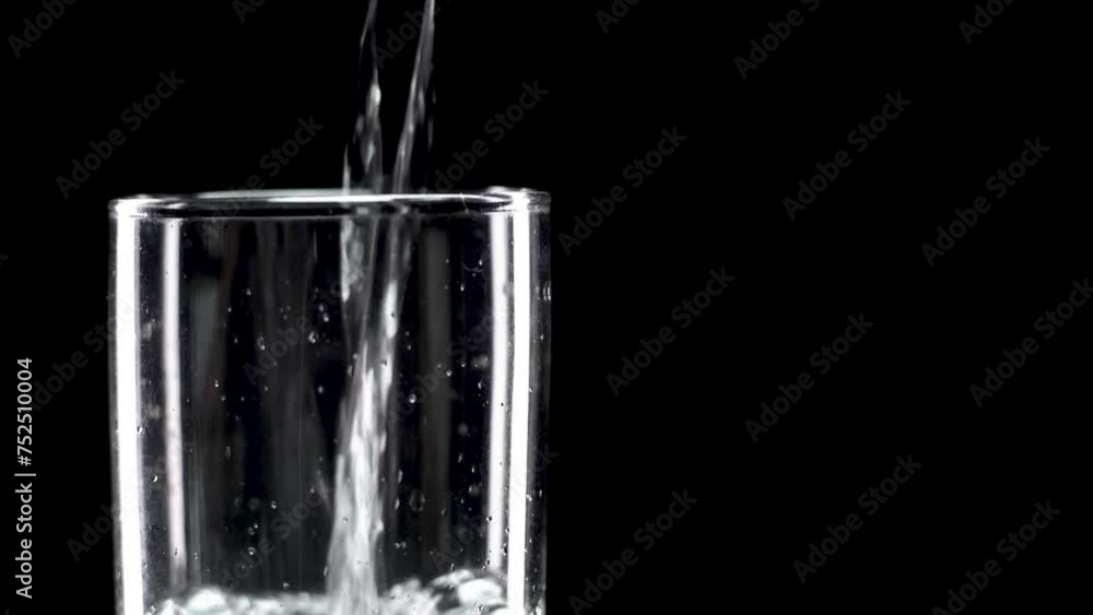 Pour drinking water into a glass of water. Pouring fresh mineral water into a glass, Mineral water in a glass on a black background. Healthy drink concept. Soft Focus, Selective Focus Pour drinking water into a glass of water. Pouring fresh mineral water into a glass, Mineral water in a glass on a black background. Healthy drink concept. Soft Focus, Selective Focus