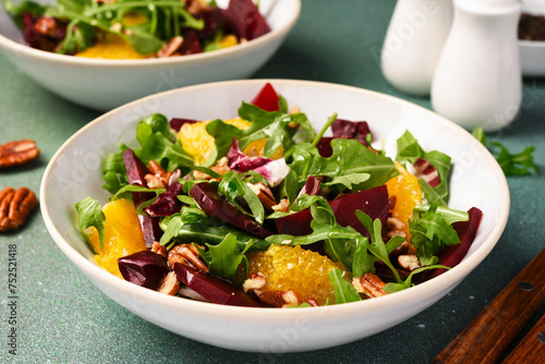 Salad with arugula, orange and beet in a plate on a green background