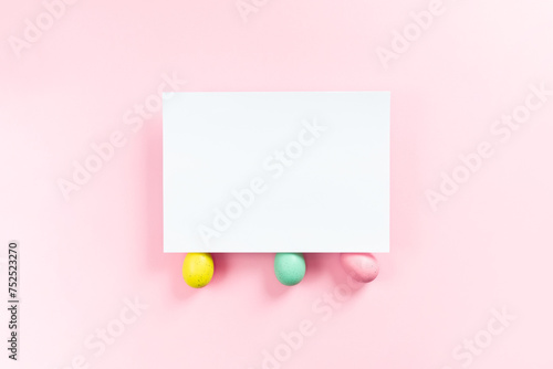 Easter mockup with empty list with three colorful eggs on pink background