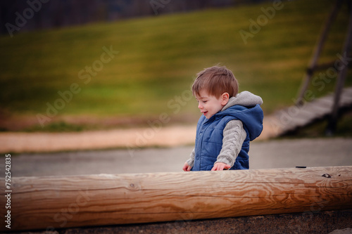 A small boy laughs with delight while playing on a wooden structure at a playground, the embodiment of childhood merriment and unbridled happiness © Иванна Емельянова