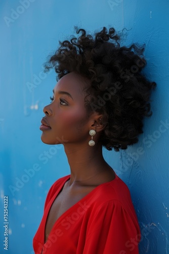 Elegant African American woman in red dress against blue background © Georgii