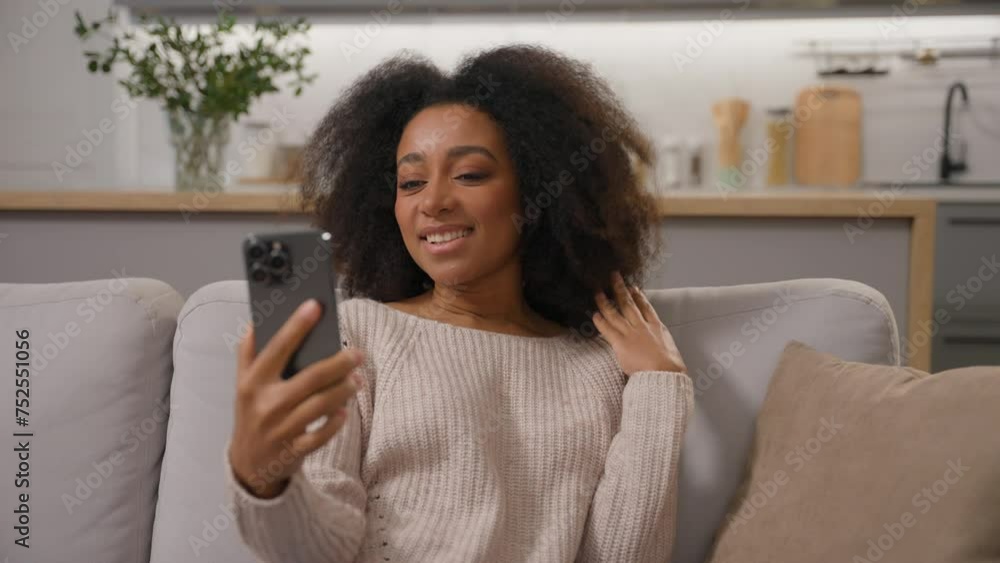 Happy smiling African american woman talking mobile phone smartphone online virtual meeting ethnic girl cheerful waving hand greeting record blog distant video call laughing with friends on home sofa Happy smiling African american woman talking mobile phone smartphone online virtual meeting ethnic girl cheerful waving hand greeting record blog distant video call laughing with friends on home sofa