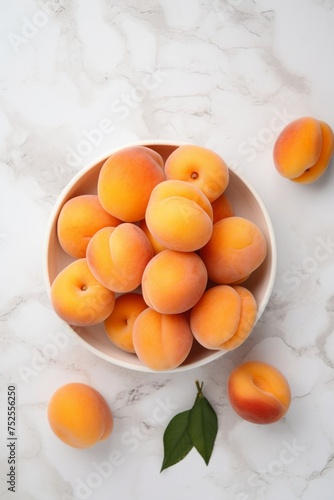 Bowl of Fresh Apricots on Marble Surface - Top View with Green Leaf Accent © Andrei