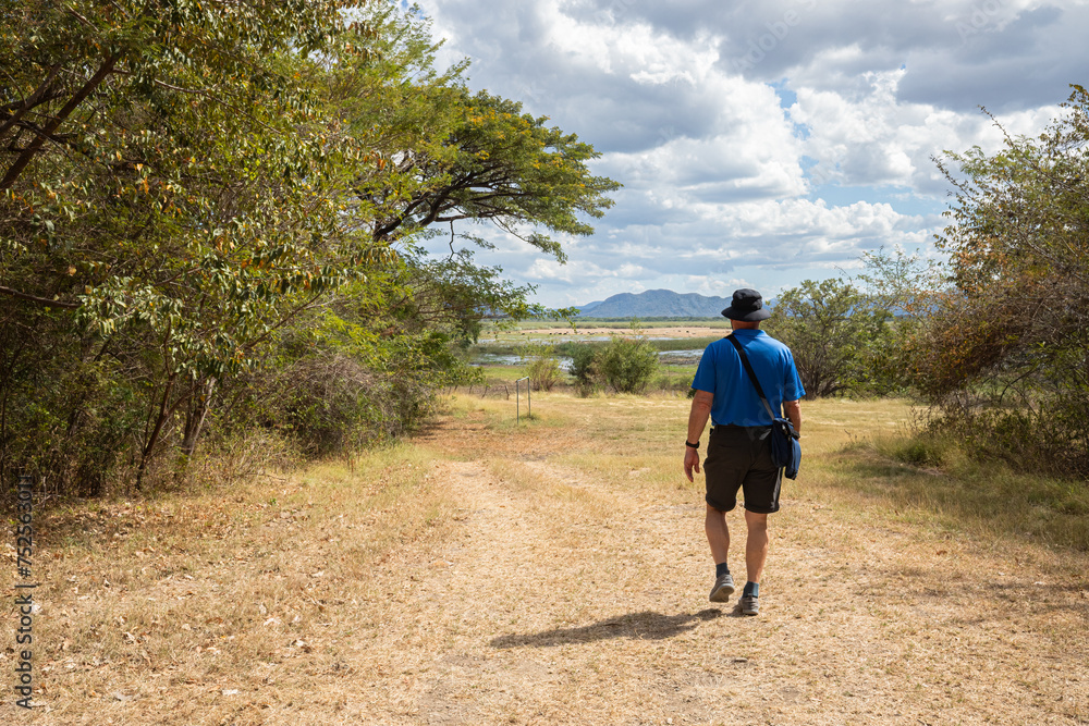 Male tourist walking on a dirt path in Palo Verde National Park in Costa Rica Male tourist walking on a dirt path in Palo Verde National Park in Costa Rica