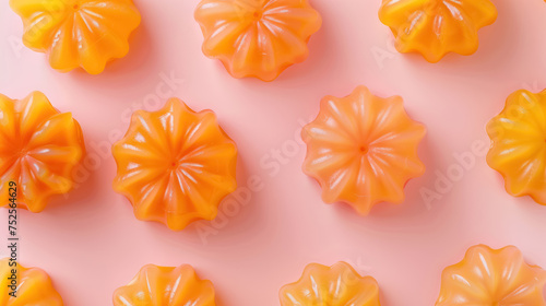 orange jelly desserts symmetrically placed on a pastel pink surface photo