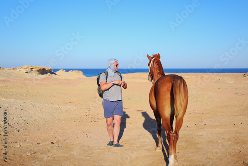 man feeding a horse in the Sahara Desert in Egypt © Olga