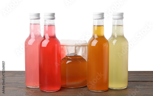Delicious kombucha in glass bottles and jar on wooden table against white background