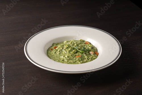 Porridge with spinach and carrots in a white plate on a black background