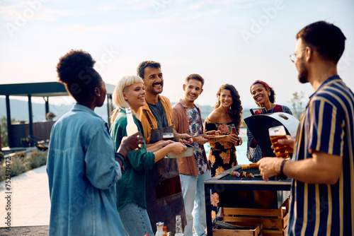 Group of happy friends talking while having barbecue party outdoors.