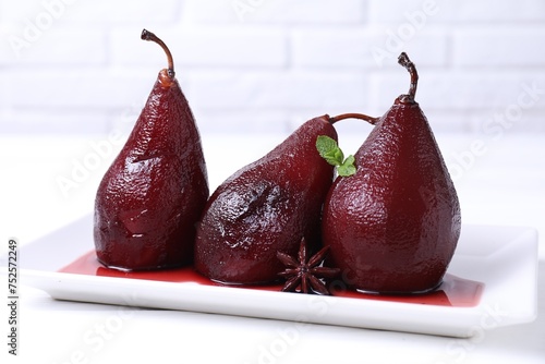 Tasty red wine poached pears with mint and anise on white wooden table, closeup