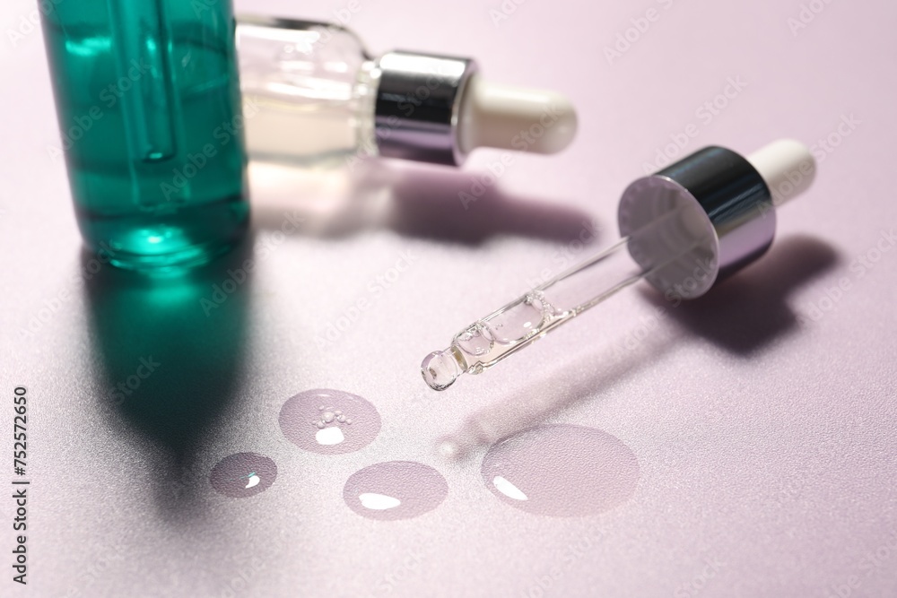 Pipette and bottles of moisturizing serum on light violet background, closeup Pipette and bottles of moisturizing serum on light violet background, closeup
