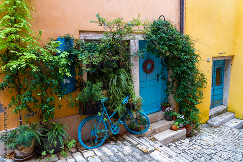 cityscape grisia street view in Rovinj Croatia with yellow houses and blue doors and bicycle decoration © Bernadett