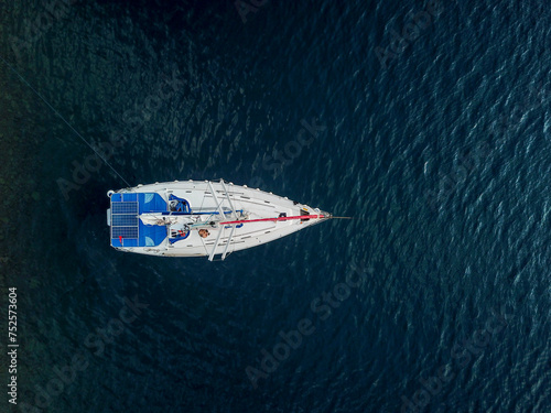 Sailing yachts without sails at anchor and mooring line at sea aerial view from drone. Blue sea water. Mediterranean yacht port with sailing boats. Yachting concept.