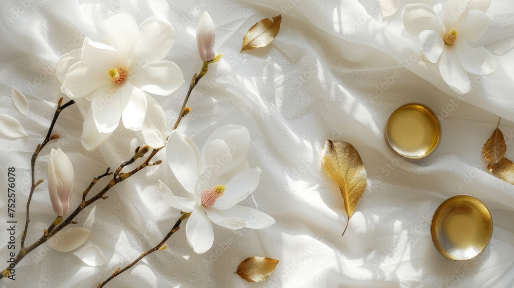 A branch with beautiful white magnolia flowers lies on a white tablecloth next to gold leaves and dishes. Nature background. Springtime A branch with beautiful white magnolia flowers lies on a white tablecloth next to gold leaves and dishes. Nature background. Springtime