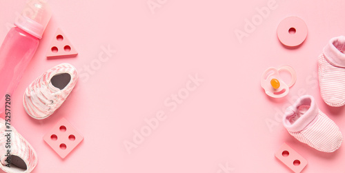 Stylish baby shoes with bottle of milk, pacifier and developing toys on pink background
