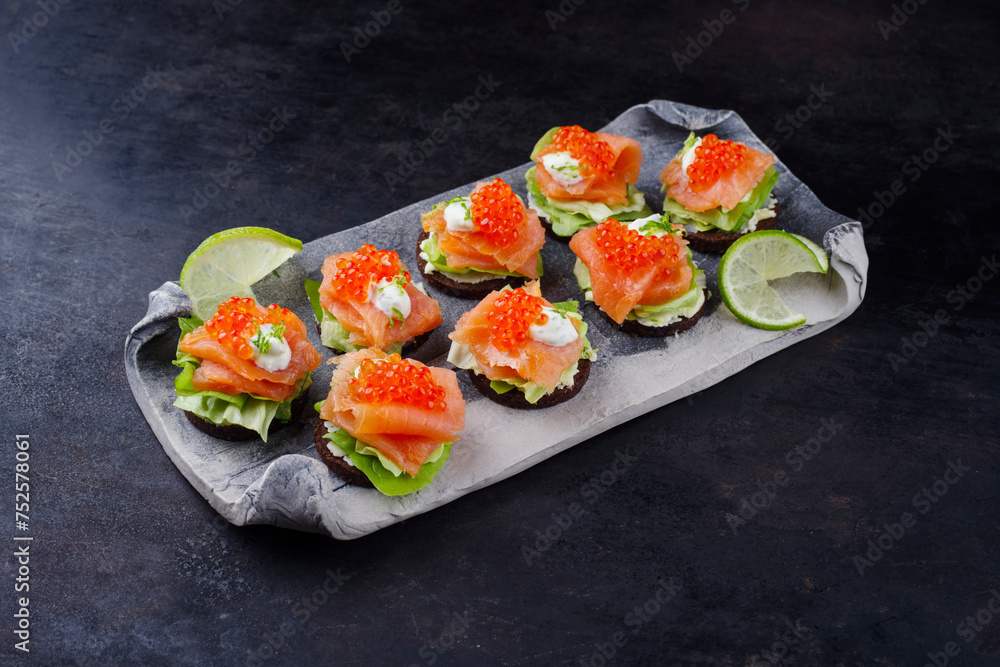 Traditional pumpernickel thaler with smoked salmon and caviar served as a snack on a design tray with copy space Traditional pumpernickel thaler with smoked salmon and caviar served as a snack on a design tray with copy space