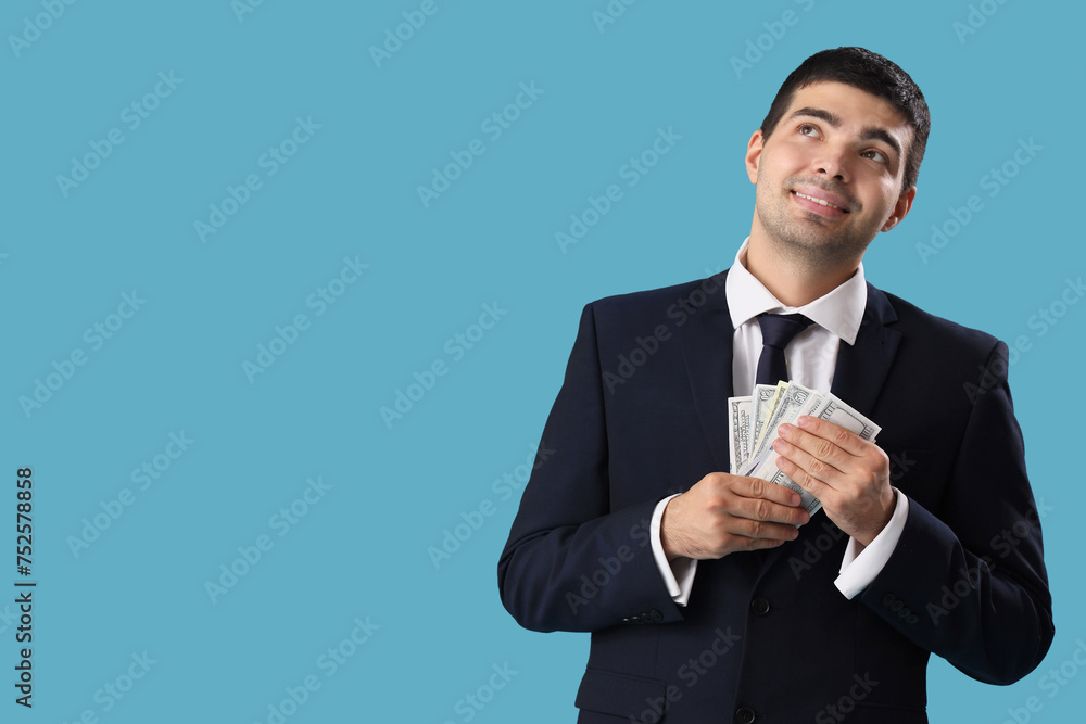 Young businessman with money on blue background Young businessman with money on blue background