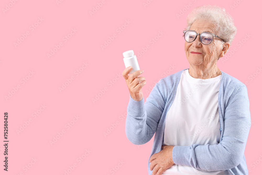 Senior woman with pill bottle on pink background Senior woman with pill bottle on pink background