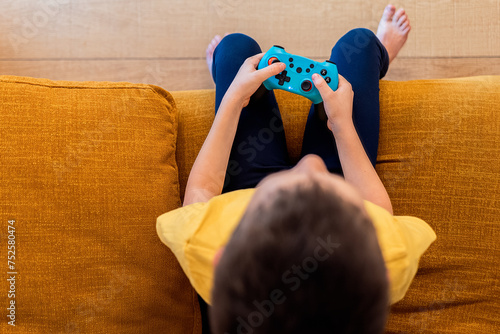 Child engrossed in video game play on sofa photo