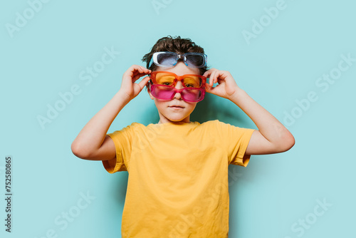 Child with multiple pairs of sunglasses on blue background photo
