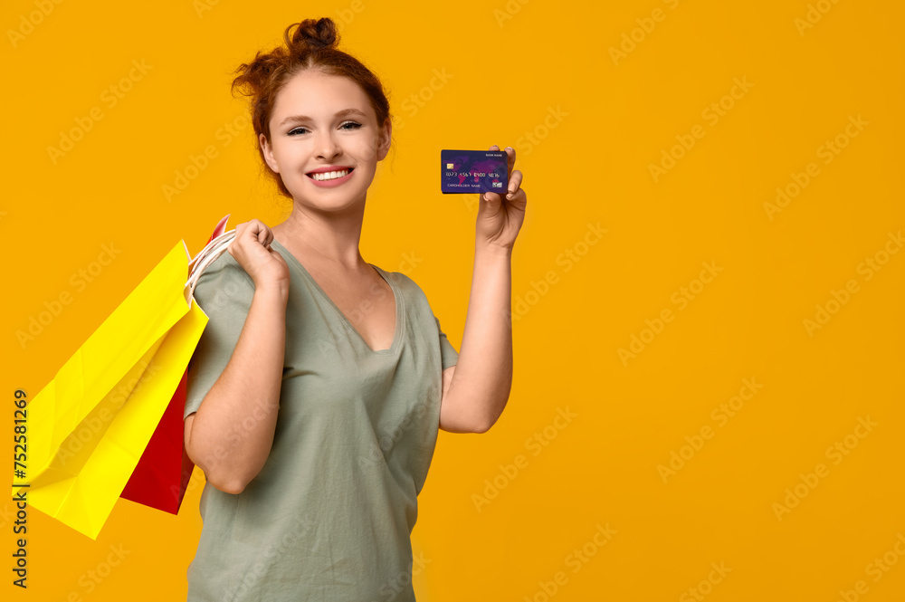 Beautiful young woman with credit card and shopping bags on yellow background Beautiful young woman with credit card and shopping bags on yellow background