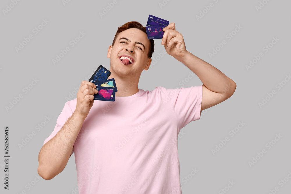 Young man with credit cards on grey background Young man with credit cards on grey background
