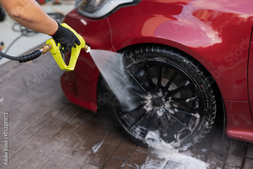 High-pressure washing of car tire and rim at auto detail photo