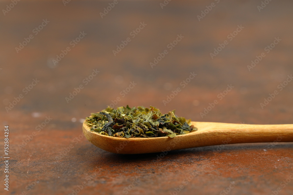 Green tea with herbs in wooden spoons on a wooden board Green tea with herbs in wooden spoons on a wooden board
