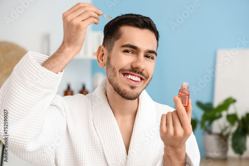 Young man applying serum fo...
