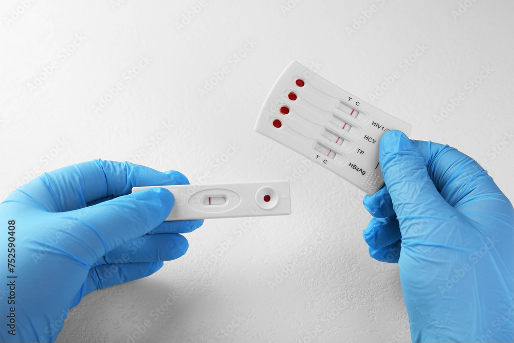 Doctor holding two disposable express tests at white table, closeup