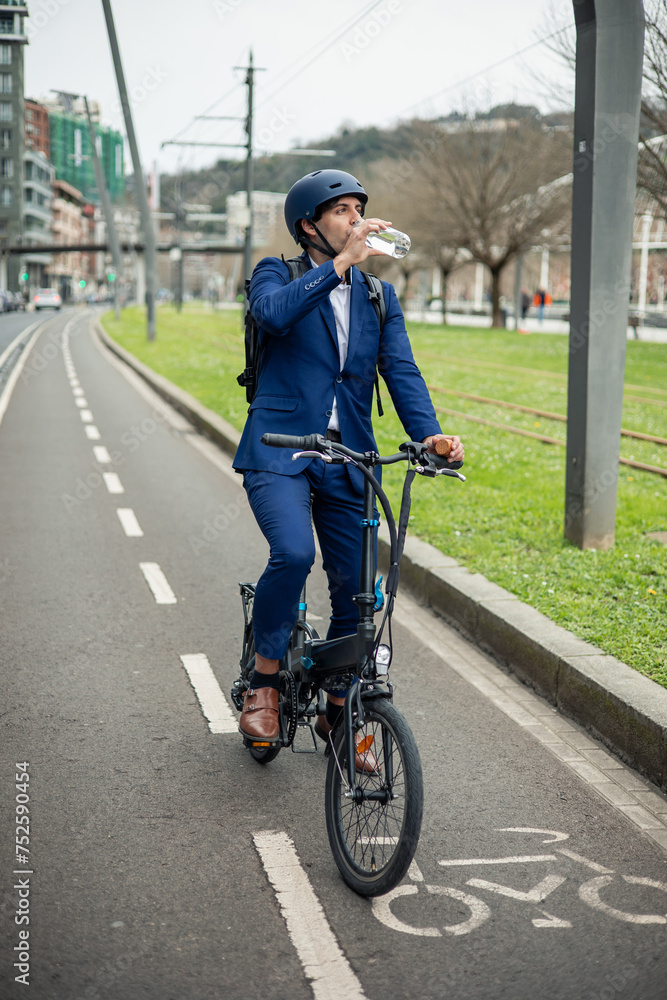 Obraz premium vertical portrait Businessman Refreshing with Water Bottle by Electric Bike on Bike Lane
