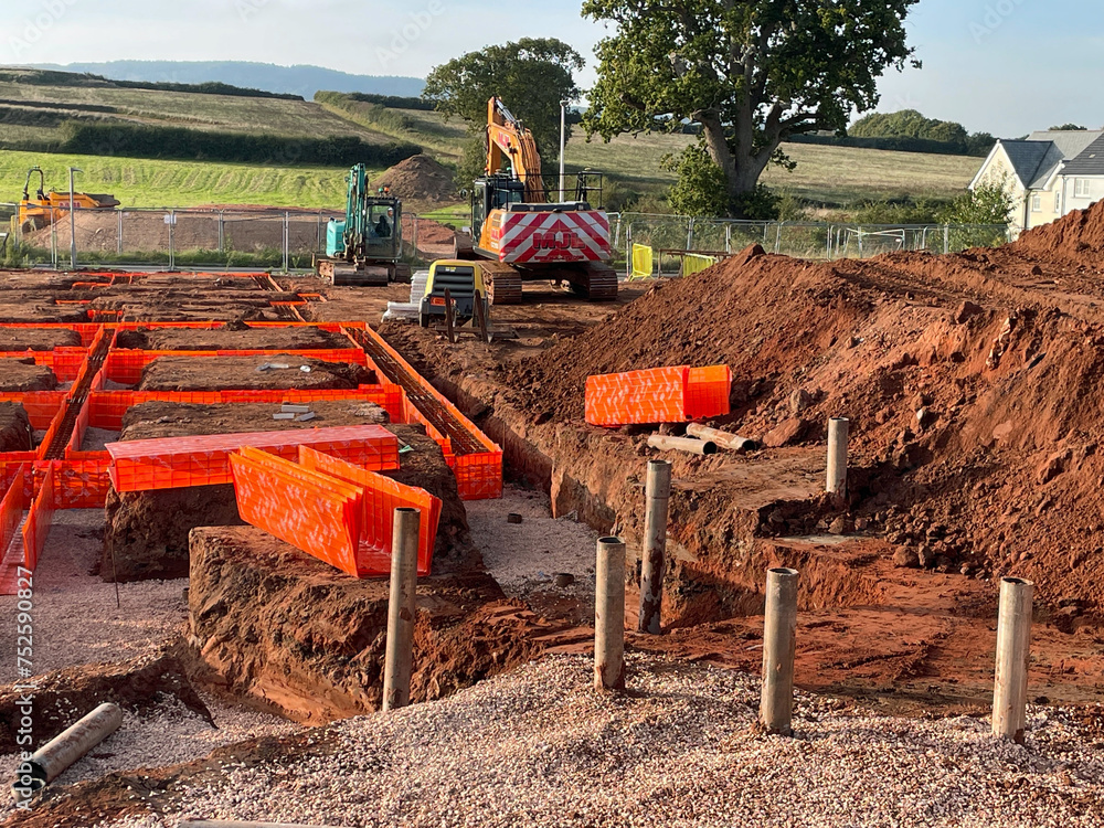 Construction site on green field site for new residential housing showing machinery and foundations with steel reinforced concrete preparations